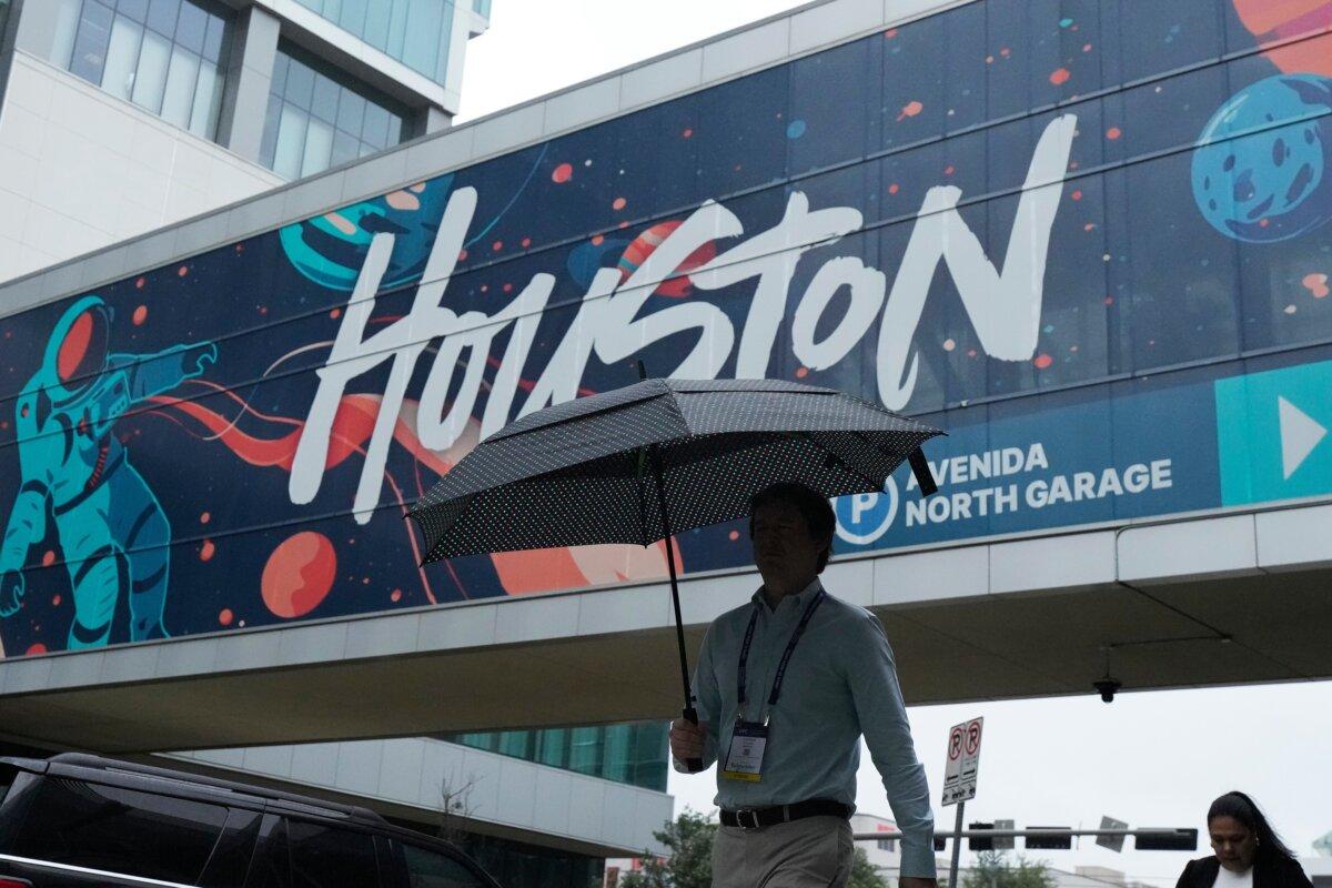 A convention attendee walks through the rain outside the George R. Brown Convention Center in Houston, Texas, on June 17, 2026. (Kevin M. Cox/AP Photo)
