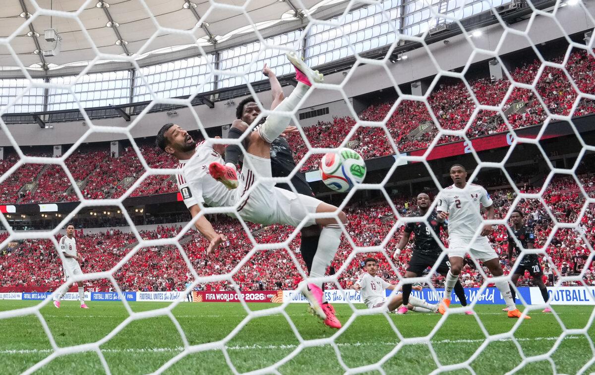 Canada's Jonathan David (back) scores past Qatar's Boualem Khoukhi during the first half of a World Cup Group B soccer match, in Vancouver, Canada, on June 18, 2026. (The Canadian Press/Darryl Dyck)