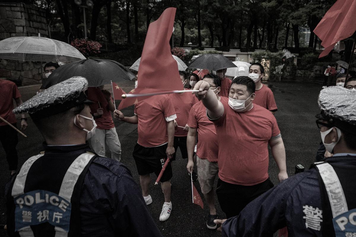 Police officers stand in front of the Chinese Communist Party supporters at Shinjuku Central Park in Tokyo, Japan, on July 1, 2021. (Takashi Aoyama/Getty Images)