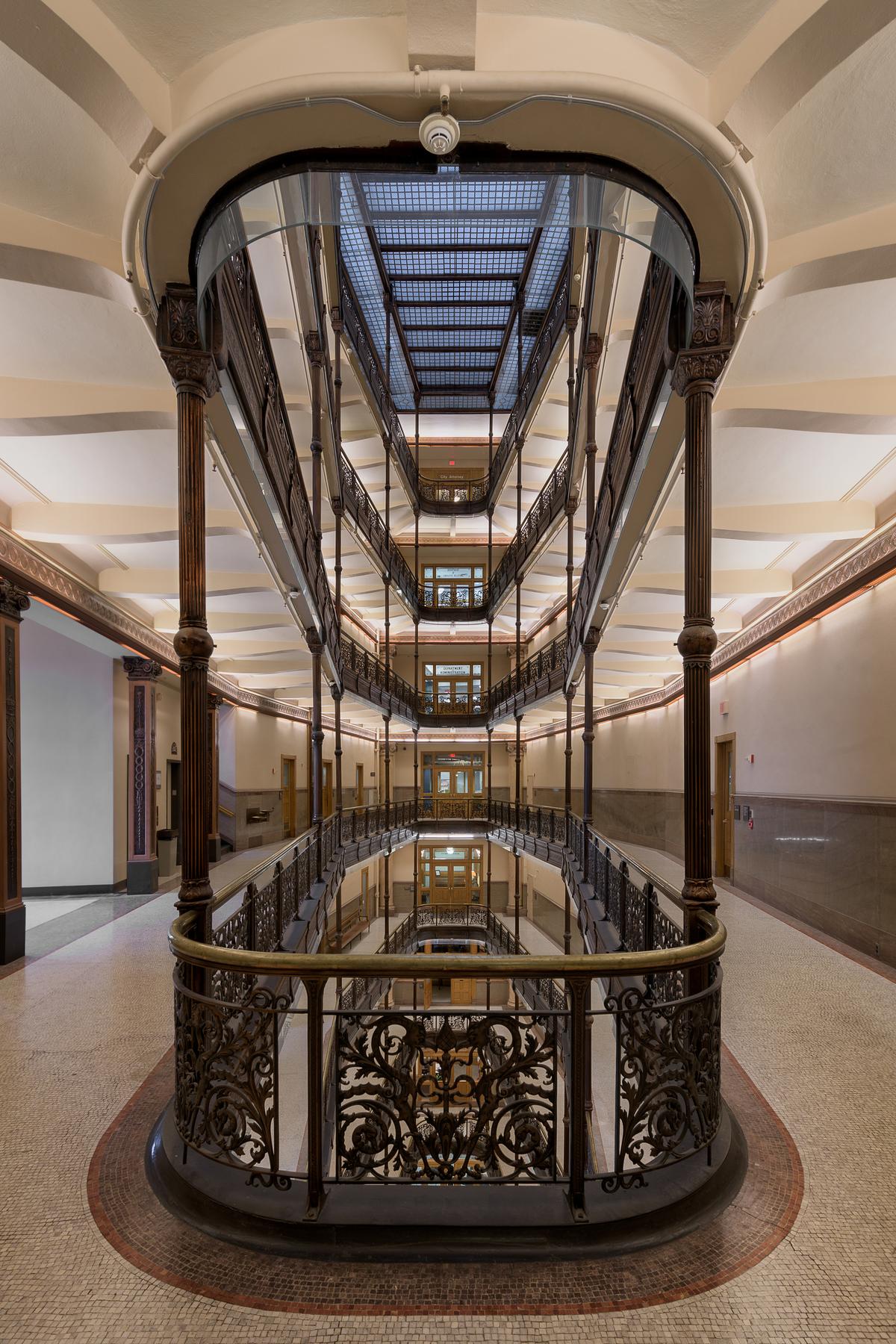 In the center of the Milwaukee City Hall building is a 20-by-70-foot open atrium situated over the stairwell. Ornate, wrought-iron railings at each level of the stairs mimic the diamond shape of the skylight. Each level of staircase railing is connected by fluted brass columns with ornamental capitals. (Nagel Photography/Shutterstock)