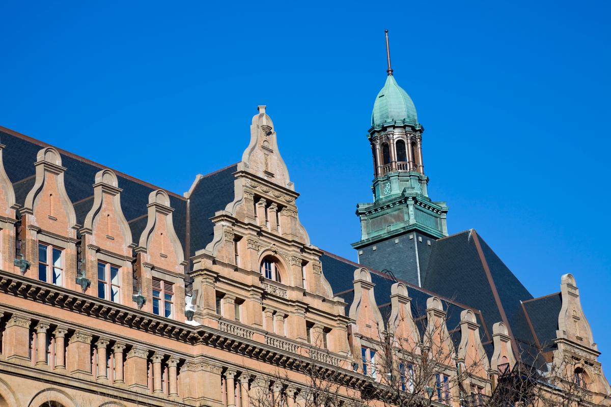 Curvilinear gables are the primary decorative element at the top of Milwaukee City Hall. The steep roof is made of slate, and a rose-colored terracotta and sandstone façade is adorned with many classical elements, including a cornice of modillions (a repeating pattern of brackets). Classical architectural features are evident in the round and square columns—all with decorative capitals. A balustrade is at the base of a four-tiered segment of roofline, which competes in this view with the copper-clad spire. (benkrut/Getty Images)
