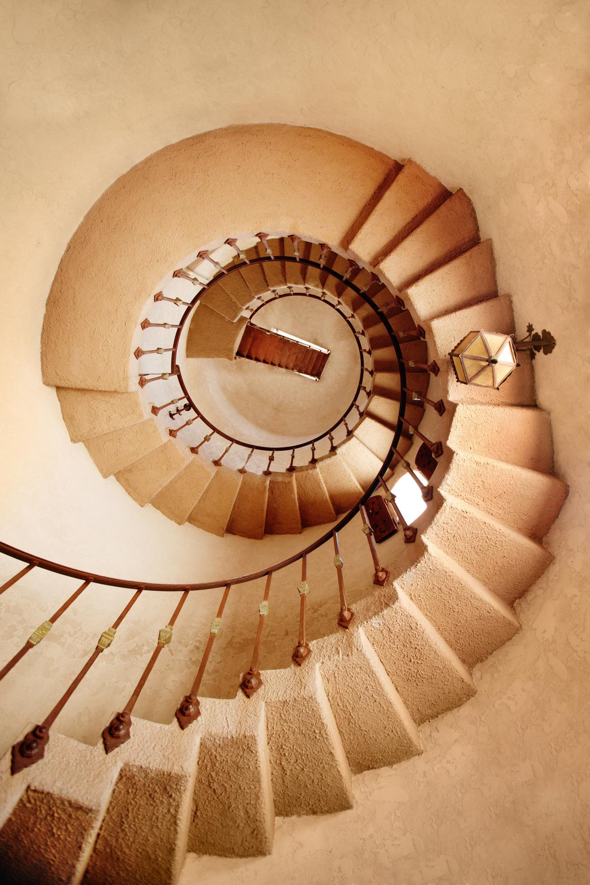 A cantilevered staircase with a wrought iron railing spirals like the interior of a nautilus shell up to the top of the observation tower. The “knuckles,” or middle section adornment on each of the balusters, resemble the capitals at the top of columns. The rivets holding the balustrade in place resemble rosettes. (B Brown/Shutterstock)
