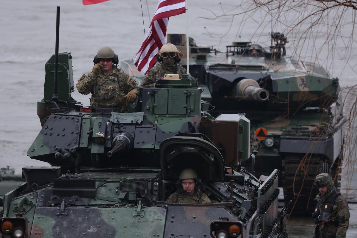 A Bradley infantry fighting vehicle (L) of the U.S. Army and a Polish Leopard 2PL main battle tank arrive on M3 amphibious rigs of the German/British Amphibious Engineer Battalion 130 after crossing the Vistula River during the NATO Dragon 24 military exercise on March 5, 2024 near Gniew, Poland. (Sean Gallup/Getty Images)
