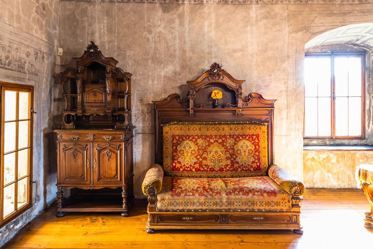 Located in the middle castle, the Palace of John of Dubovec is staged as a period-furnished living area, showcasing Renaissance-style wooden dressers and a wood-framed sofa upholstered in patterned fabric. Deeply recessed stone-framed windows reflect the fort's architecture. Nearly all furniture here dates from the late 19th and early 20th centuries, brought in to evoke the castle's Renaissance and baroque past. (Tartezy/Shutterstock)
