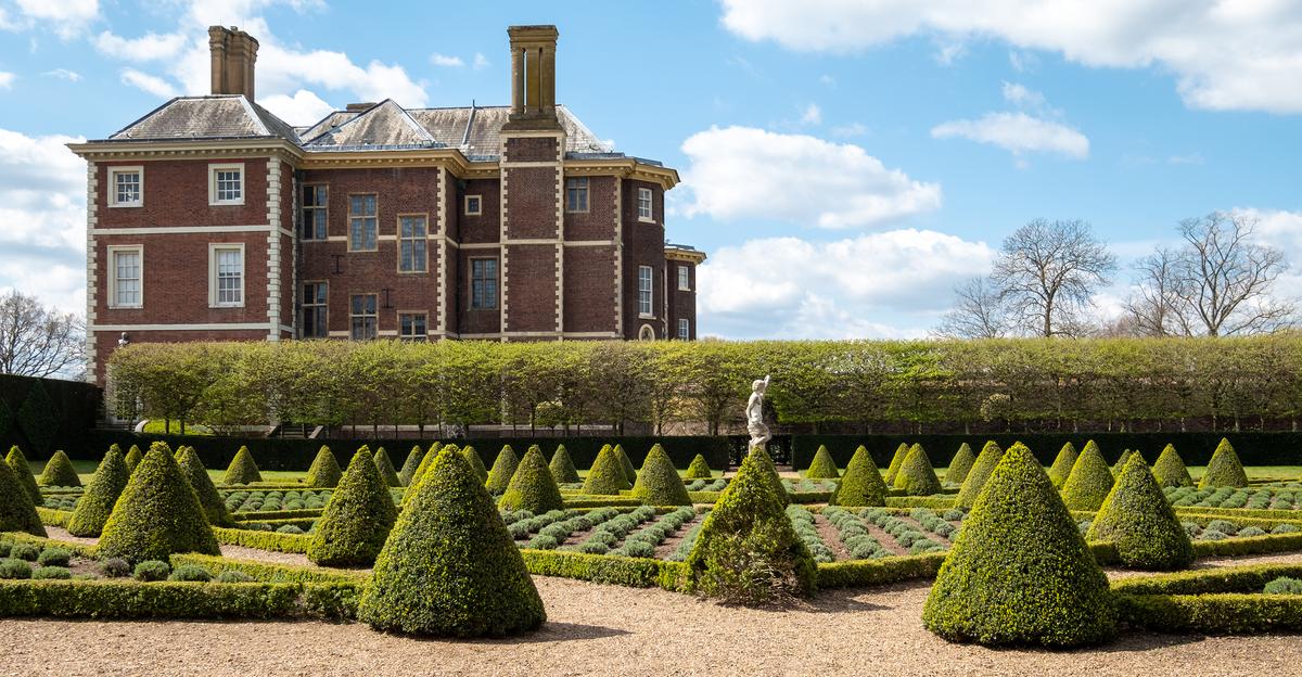 Even though the almost 100 original cherry trees have been replaced with carefully shaped low hedges that serve as triangular and diamond-shaped borders for lavender, this garden at Ham House is still called Cherry Garden. Part of the 30 acres of gardens at Ham House, Cherry Garden, with its cone-shaped topiaries, features a statue of Bacchus, the Roman god of wine. The side of the mansion is trimmed in white brick quoin work that contrasts the red brick. (Lois GoBe/Shutterstock)