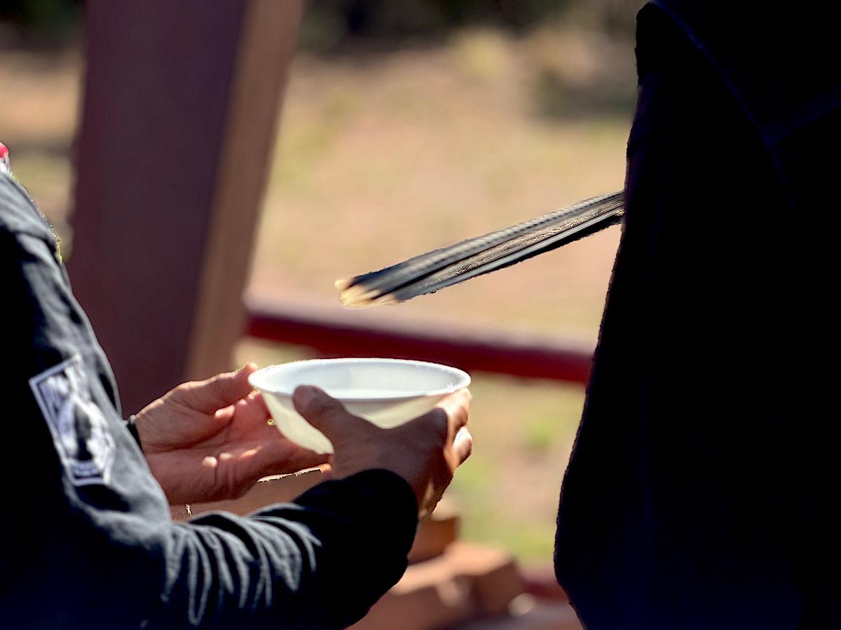 Participants in a flag-passing ceremony in Window Rock, Ariz., douse a memorial plaque honoring fallen Navajo veterans on July 28, 2026. (Allan Stein/The Epoch Times)