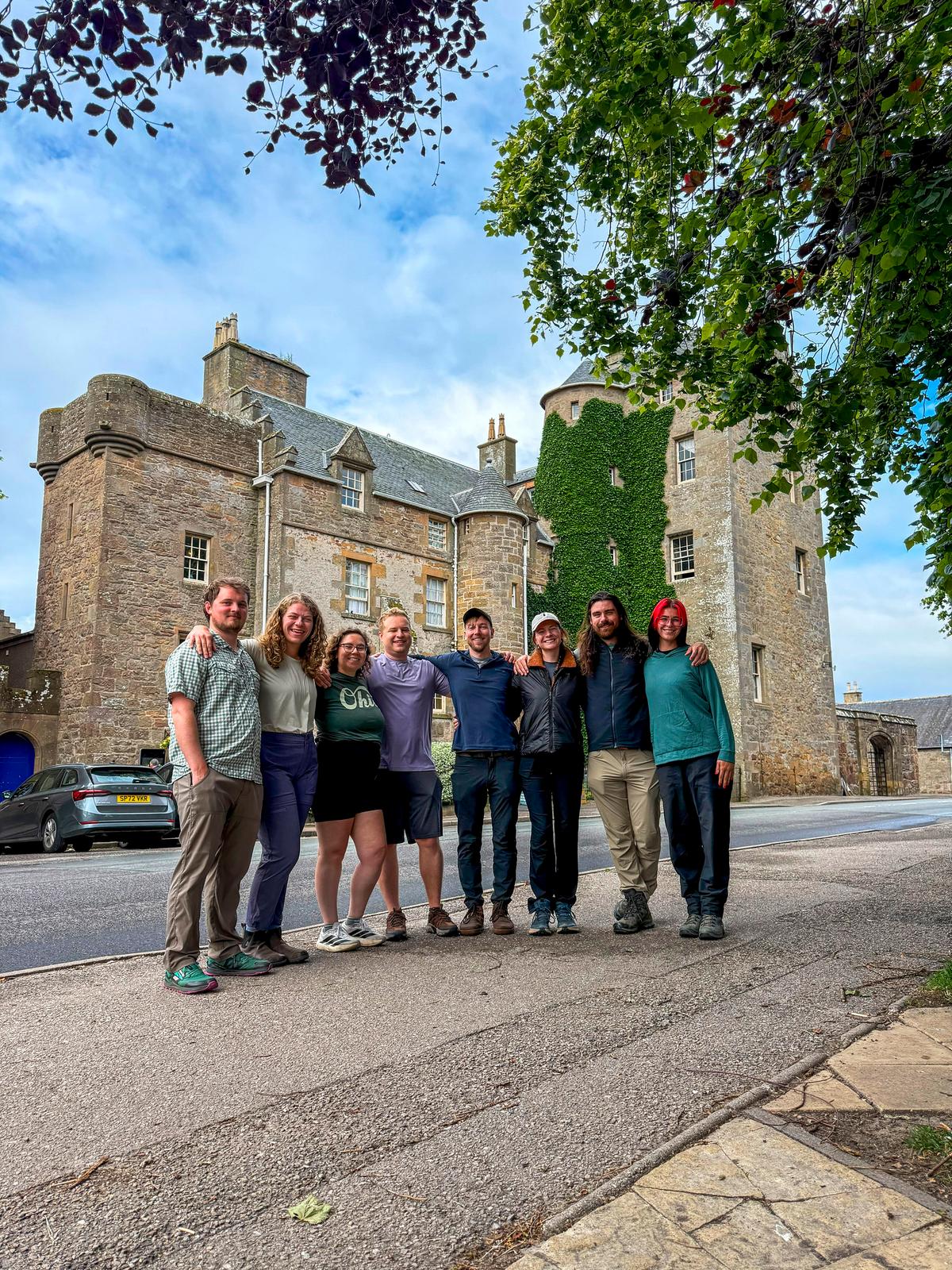 A group of happy travelers, from left, Elijah Hawley, Sarah Holm, Mara Díaz, Owen Osterling, Patrick Connolly, Karissa Bellile, Matt Starkey and Leigh Bacho, congregate outside the Dornoch Castle Hotel in the Highlands of Scotland on July 3, 2026. (Patrick Connolly/Orlando Sentinel/TNS)