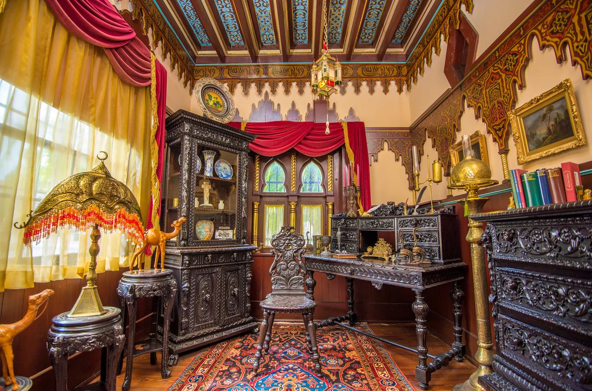 A gold gilt and blue design is painted between the exposed beams on the Prayer Room’s tray ceiling. The heavily carved, 17th-century German black walnut furnishings in the room were originally used by Franklin Smith, since the space was his study and office. Most of the mansion’s lighting fixtures are original, including the Moroccan hanging lantern and the hand-pierced brass lamp with beading. Hand-carved and painted overlay decorative paneling serves as crown molding at the ceiling as well as decorations on the walls around the room. (Villa Zorayda Museum)
