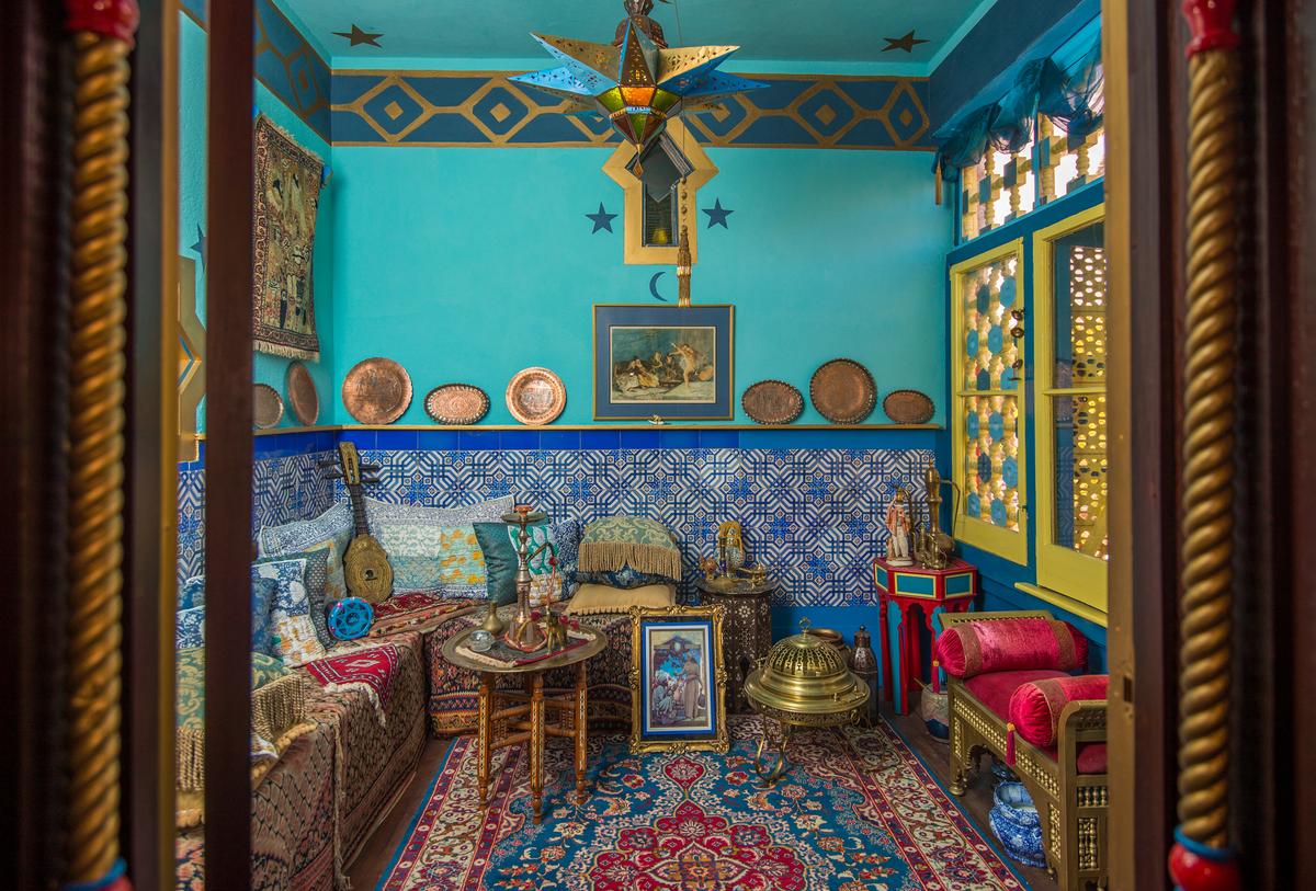 This is referred to as the Harem Room for two reasons: The cutout window design allows people to see out but not in, and family members gathered here. Stars, the sun, and crescent moons are motifs throughout Villa Zorayda, including on the aqua-blue walls and ceiling. The hand-pierced brass light fixture is a star shape. Hand-painted tile embellishes the walls up to the chair railing. (Villa Zorayda Museum)