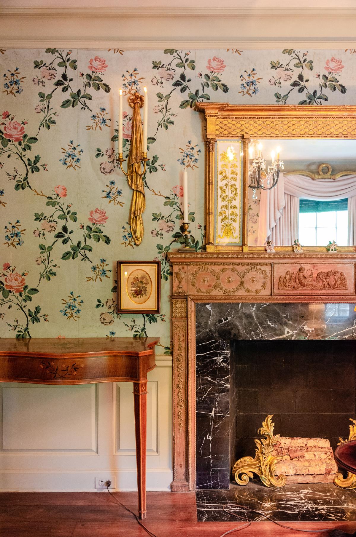 The Reception Room is located on the lower level at the front of Longue Vue House, providing an inviting space for family and guests. It features wallpaper designed by Nancy McClelland, author of the first comprehensive American book on wallpaper. The low ceiling, warm wood floors, furnishings, and carved period mantelpiece create an intimate setting for entertaining. (Longue Vue House and Gardens)