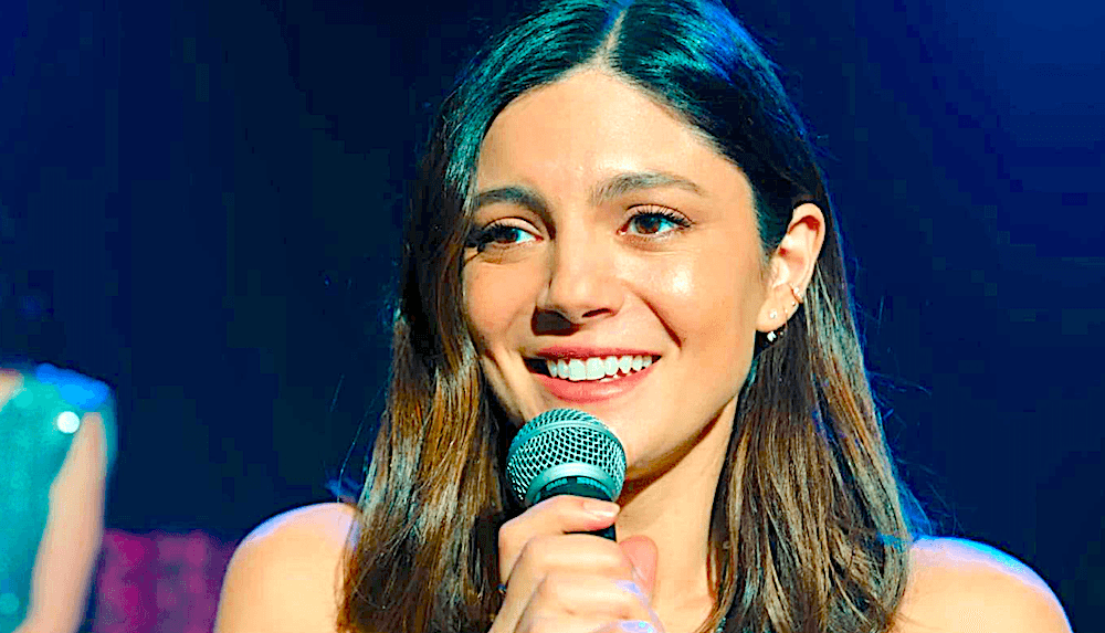 To her horror, jingle-singer Allie (Monica Barbaro) has successfully been wheedled, cajoled, and forcibly pushed onstage to perform, in "One Night Only." (Universal Pictures)