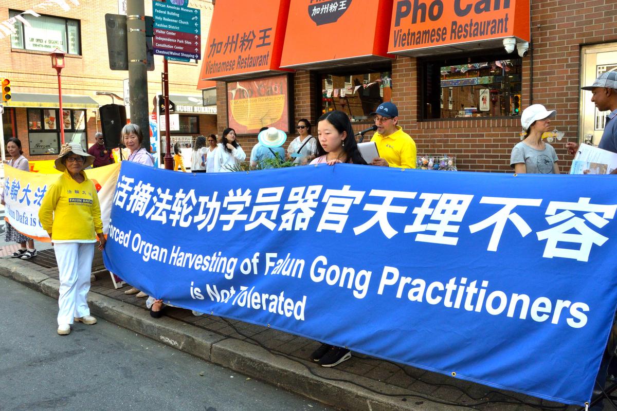 Tian Zhongfeng, in front of the banner, at the rally in Philadelphia on Aug. 15, 2026. (Frank Liang/The Epoch Times)