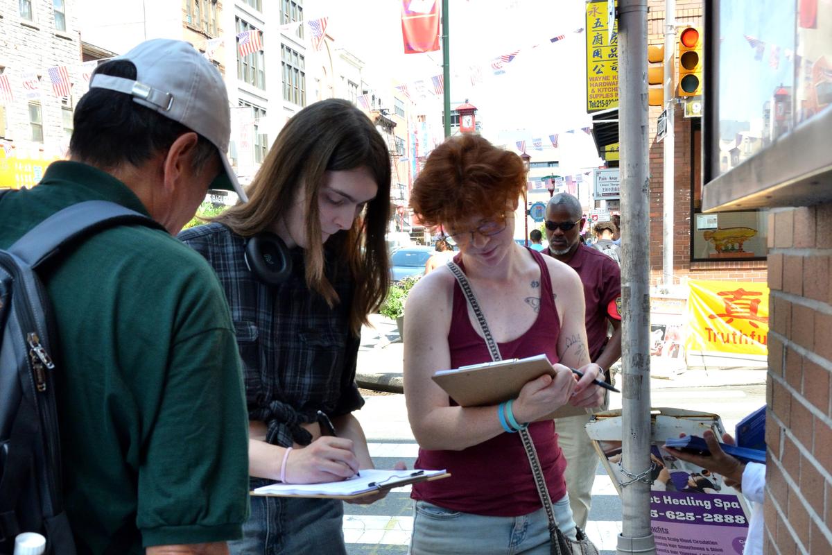 Security professional Amy (C) and artist Mula (R) sign the petition for S. 4009 in Philadelphia on Aug. 15, 2026. (Frank Liang/The Epoch Times)