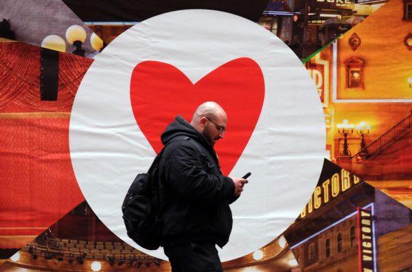 A man texts on his smartphone as he walks along a street in New York on March 4, 2015. Social dating app Tinder announced that it will limit right swipes (to like or accept) in an effort to emulate real-life relationships. (Jewel Samad/AFP/Getty Images)