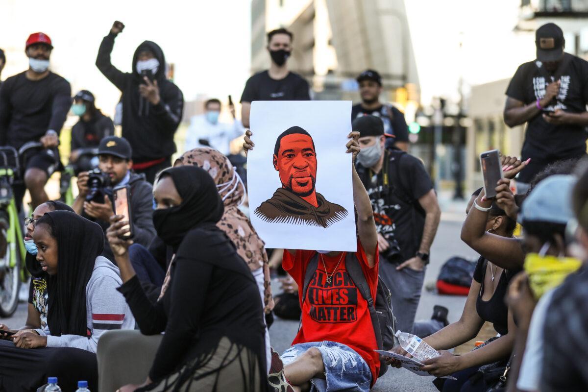 Protesters hold signs during a march from St. Paul to US Bank Stadium in Minneapolis via the Saint Anthony Falls bridge on the fourth day of protests and violence following the death of George Floyd, in Minneapolis, Minn., on May 29, 2020. (Charlotte Cuthbertson/The Epoch Times)