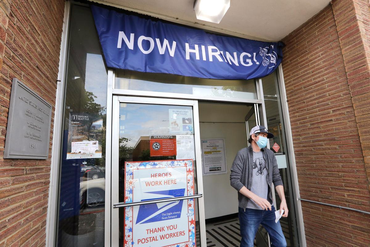 A customer walks out of a U.S. Post Office branch and under a banner advertising a job opening, in Seattle, Wash., on June 4, 2020. (Elaine Thompson/AP Photo)