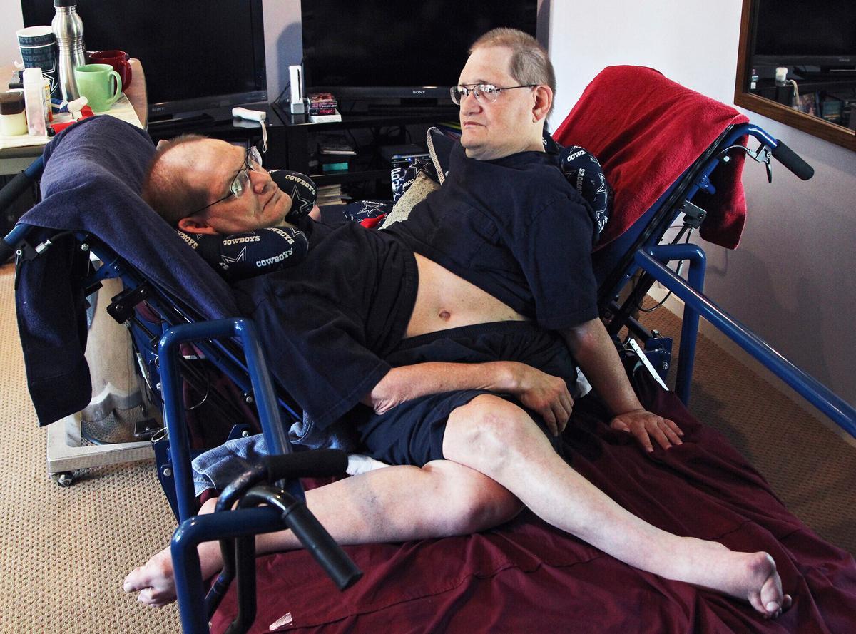 FILE - Donnie, left, and Ronnie Galyon sit inside their Beavercreek, Ohio, home, in a Wednesday, July 2, 2014, file photo. The world’s longest-surviving conjoined twins died on July 4, 2020, at the age of 68. (Drew Simon/Dayton Daily News via AP)