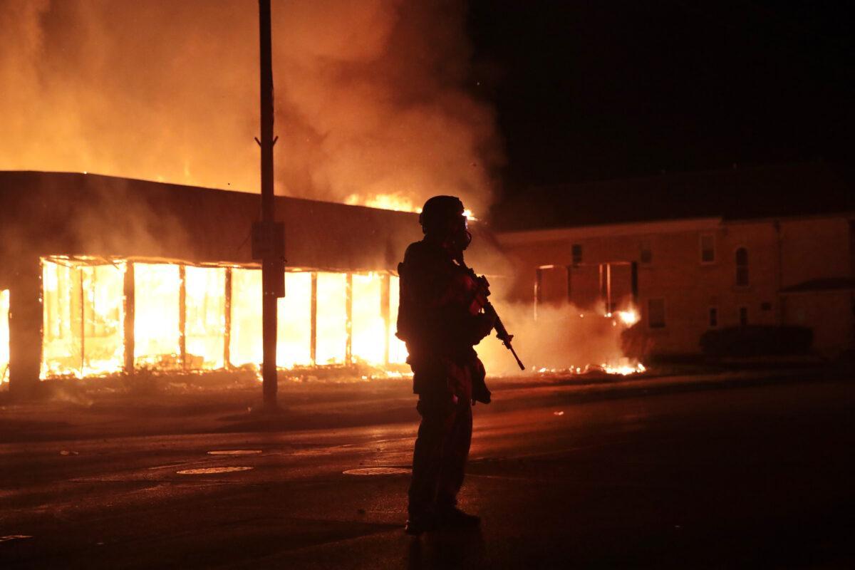 A police officer stands guard in front of a burning business during a second night of rioting in Kenosha, Wis., on Aug. 24, 2020. (Scott Olson/Getty Images)
