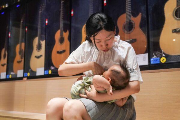 Wang Chao feeding her child at her guitar store in Shanghai, China, on Aug. 5, 2020. (STR/AFP via Getty Images)