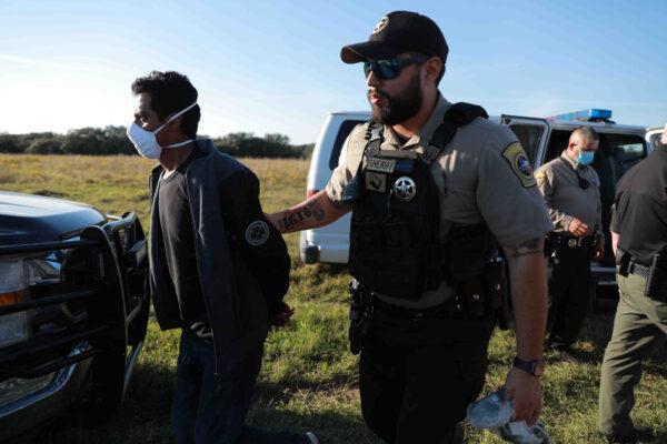 A Goliad County Sheriff’s Deputy apprehends an illegal immigrant in Goliad, Texas, on Nov. 23, 2021. (Charlotte Cuthbertson/The Epoch Times)