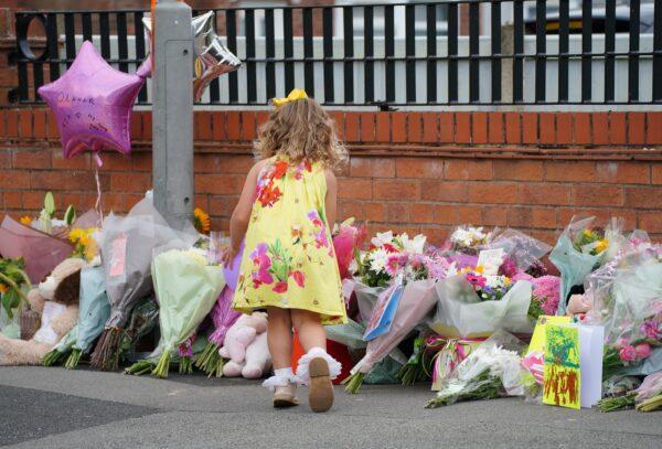 A young girl lays a tribute to murdered nine-year-old Olivia Pratt-Korbel outside her home in Kingsheath Avenue, Knotty Ash, Liverpool, on Aug. 24, 2022 (PA).