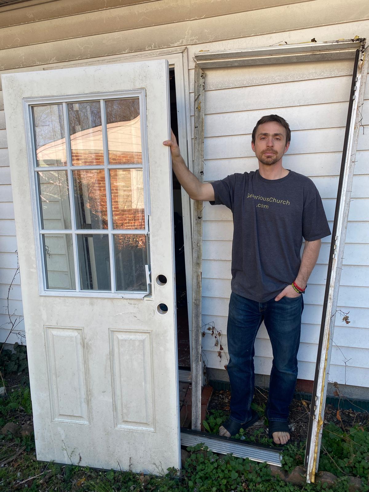 Jonathan Darnel stands beside a door that the FBI smashed in during a predawn raid on his house. Photo taken near Alexandria, Virginia. (Courtesy of Jonathan Darnel)