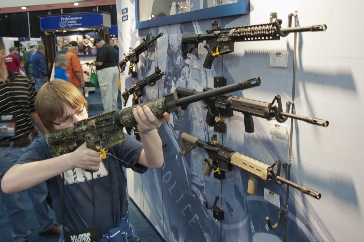 A young man who chose not to give his name sizes-up an assault-style rifle during the National Rifle Association's annual convention in 2013. (AP Photo/Steve Ueckert)