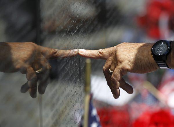 A visitor points to the name of one who died during the Vietnam War, inscribed on the marble wall of the Vietnam Veterans Memorial, ahead of Memorial Day celebrations in Washington, on Sunday, May 26, 2013. (AP Photo/Molly Riley)