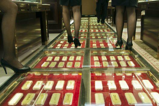 Chinese sales staff walk along an aisle paved with gold bars at a gold exchange house in Kunming, China, Dec. 11, 2012. (STR/AFP/Getty Images)