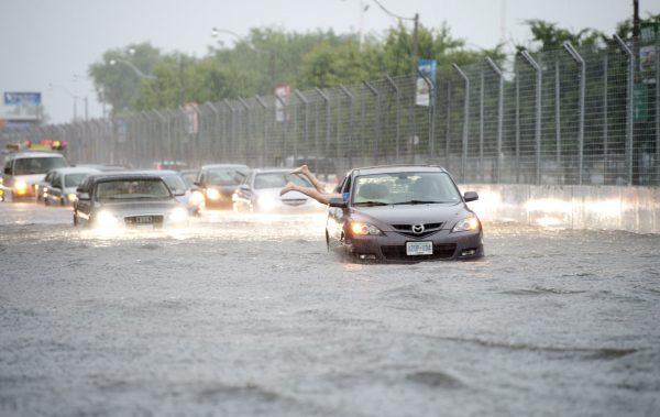 A woman gets back in her car in flood water on Lakeshore West during a storm in Toronto on Monday, July 8, 2013. (AP Photo/The Canadian Press, Frank Gunn)