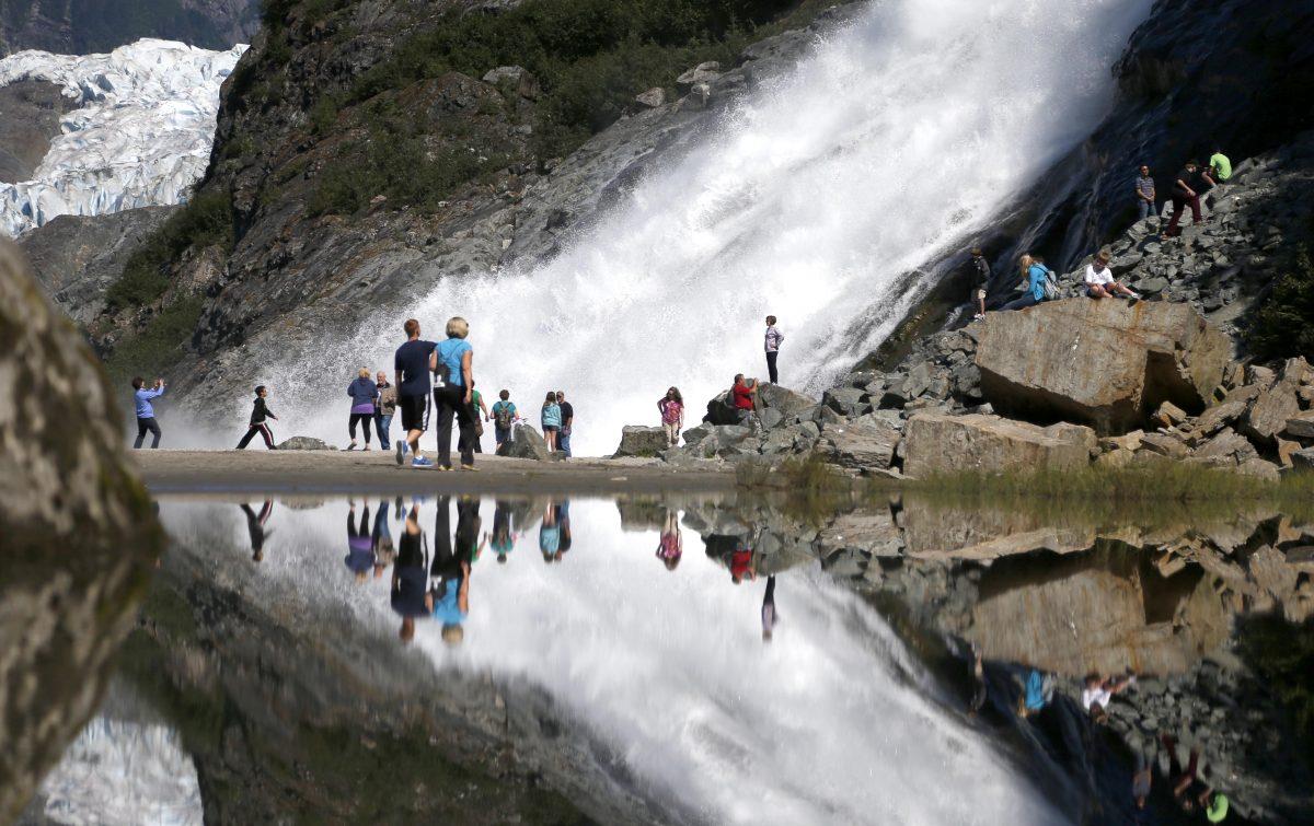 AUG 1: Tourist at the Mendenhall Glacier in the Tongass National Forest are reflected in a pool of water as they make their way to Nuggett Falls Wednesday, July 31, 2013, in Juneau, Alaska (AP Photo/Charles Rex Arbogast)