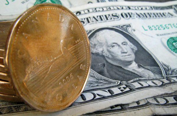 Canada Braces for 25 Percent US Tariffs | USNN World News Canadian dollars, or loonies, sit on U.S. dollar bills in a file photo. (The Canadian Press/Paul Chiasson)