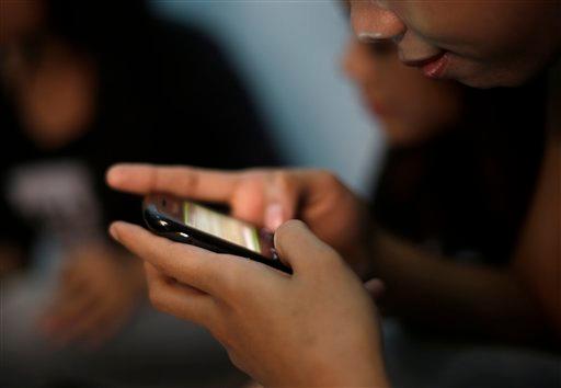 A teenage sex worker checks messages on her mobile phone at a boarding house in Bandung, West Java, Indonesia, on Aug. 1, 2013.  (Dita Alangkara/AP Photo)
