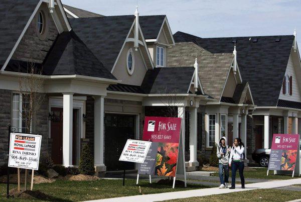 People walk past homes for sale in Oakville, Ont., in this file photo. (Nathan Denette/The Canadian Press)