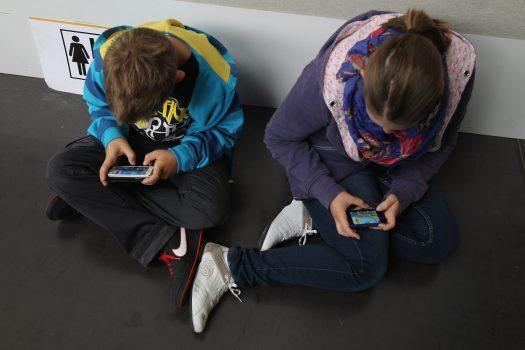 Two children play video games on their phones. The world is seeing an explosion of smart phone usage that will have a long-term impact on human relationships. (Sean Gallup/Getty Images)