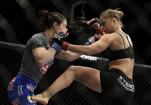 Ronda Rousey, right, kicks Sara McMann during a UFC 170 mixed martial arts women's bantamweight title fight on Saturday, Feb. 22, 2014, in Las Vegas. Rousey won by TKO. (AP Photo/Isaac Brekken)