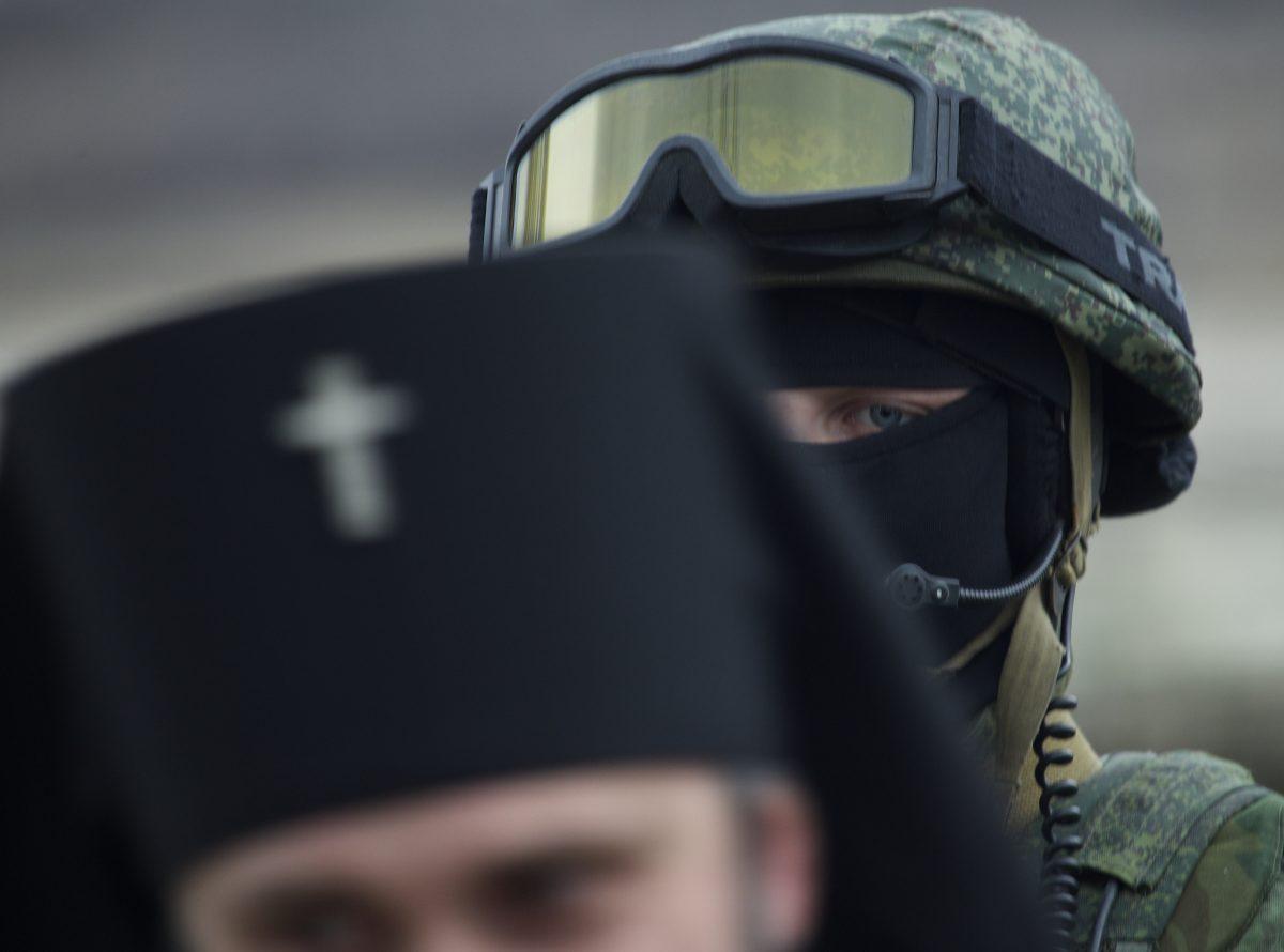 A Russian soldier is seen behind Ukrainian Orthodox Archbishop Clement (front) outside of a Ukrainian military base in the village of Perevalne, outside of Simferopol, Ukraine, on March 2, 2014. (Ivan Sekretarev/AP Photo)