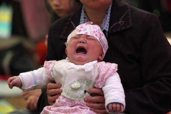 A baby is crying in her mother’s arms in China, in April 2013. Poverty, illicit profiting, and China’s coercive one-child policy drive baby trafficking in China. (AFP/Getty Images)