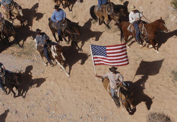  The Bundy family and their supporters fly the American flag as their cattle were released by the Bureau of Land Management back onto public land outside of Bunkerville, Nev. on April 12, 2014. (AP Photo/Las Vegas Review-Journal, Jason Bean)