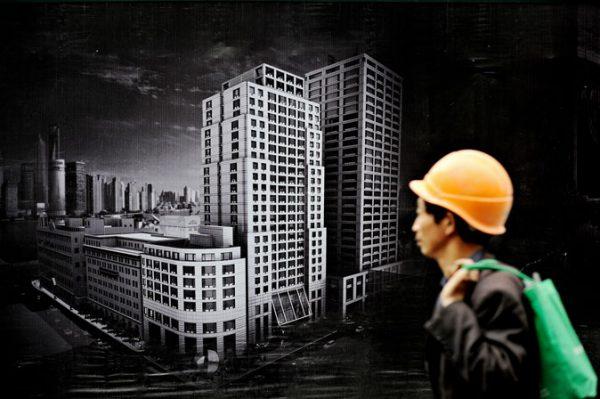 A worker walks past a billboard advertising a new real estate project in Shanghai. (Philippe Lopez/AFP/Getty Images)