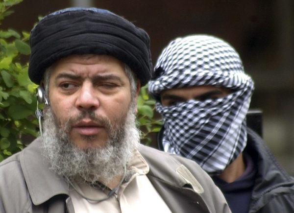 Muslim cleric Mustafa Kamel Mustafa arrives with a masked bodyguard to conduct Friday prayers in the street outside the closed Finsbury Park Mosque in London on April. 30, 2004. The 55-year-old Egyptian cleric, who also goes by the alias Abu Hamza al-Masri, was found guilty on May 19, 2014 in federal court in New York of providing material support to terrorist organizations. (Max Nash, File/AP Photo)