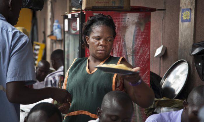 34-year-old single mother Madinah Nalukenge serves dishes to customers at her food stall, frequented by transport operators, on the edge of a bus terminal in the capital Kampala, Uganda, May 30, 2014. (AP Photo/Rebecca Vassie)