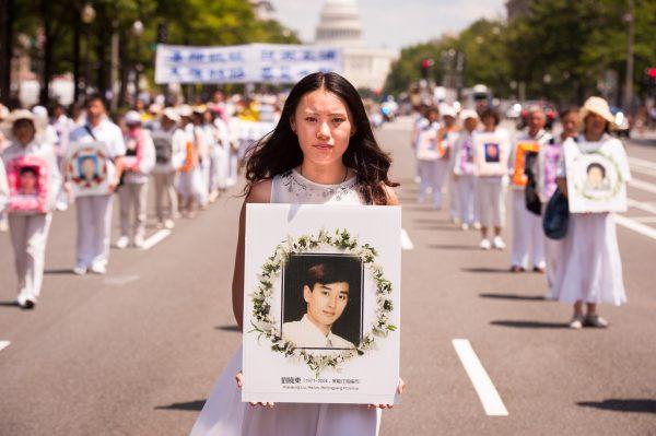 A women holds a photo of a fellow Falun Gong practitioner, killed for his beliefs, during a parade calling for an end to the persecution in China, in Washington, D.C., on July 17, 2014. (Edward Dai/Epoch Times)