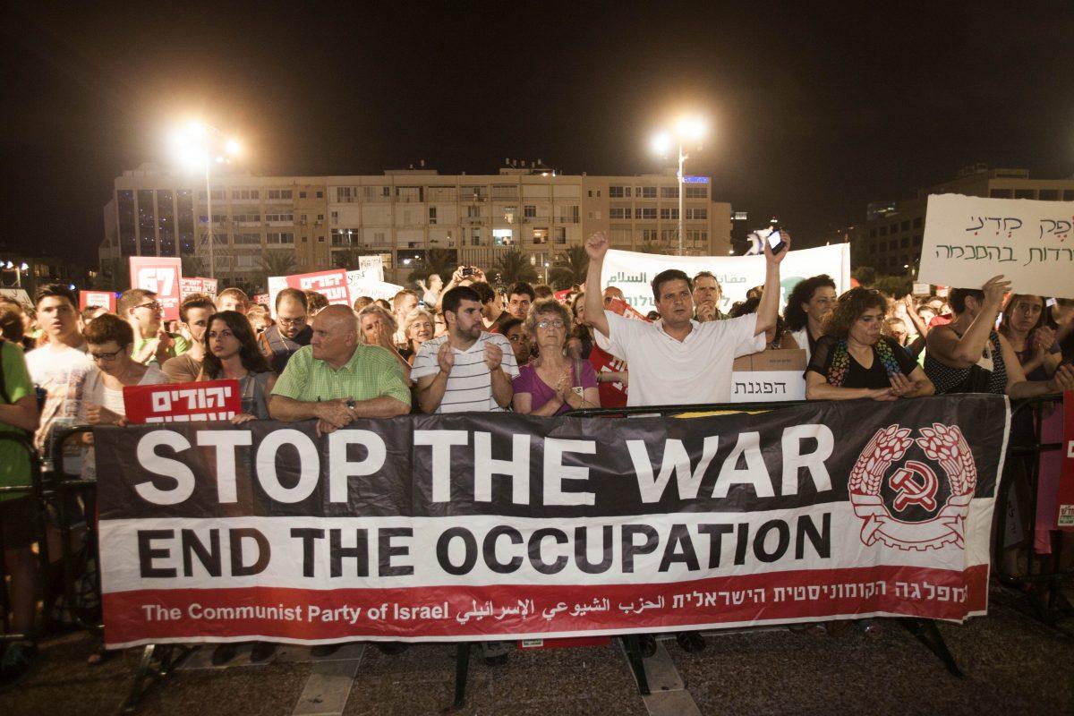 Israeli left-wing activists hold a sign during a demonstration against an earlier Gaza war, in Tel Aviv, Israel on July 26, 2014. (AP Photo/Dan Balilty)