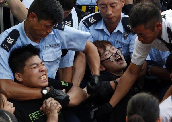 Protesters are taken away by police officers after hundreds of protesters staged a peaceful sit-ins overnight on a street in the financial district in Hong Kong Wednesday, July 2, 2014, following a huge rally to show their support for democratic reform and oppose Beijing's desire to have the final say on candidates for the chief executive's job. (AP Photo/Kin Cheung)