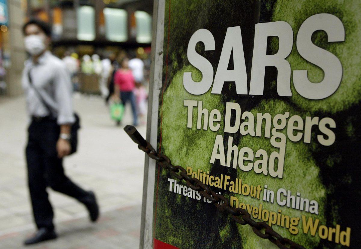 A man wearing a mask to protect himself from SARS, walks by a news headline at a newsstand on a street in Hong Kong, in May 2003. (Peter Parks/AFP/Getty Images)