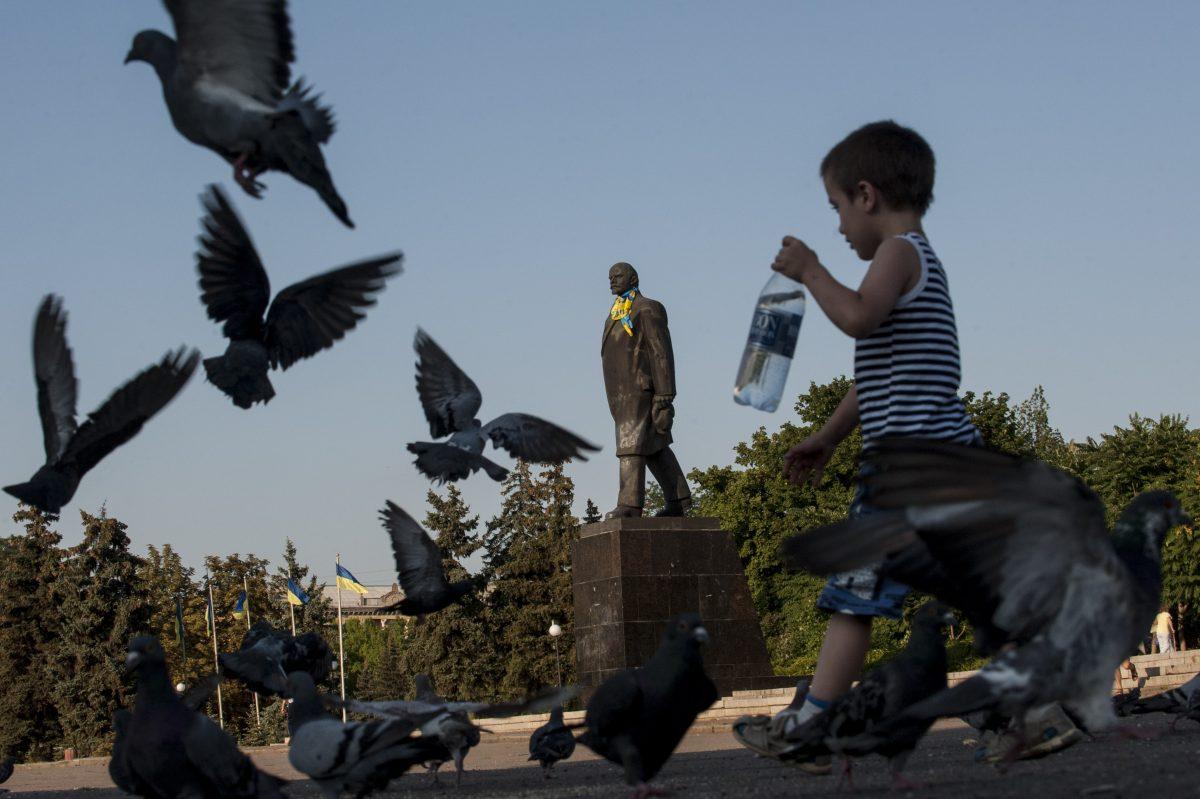A Ukrainian boy walks past a statue of Soviet Union founder Vladimir Lenin decorated with a Ukrainian national flag in Kramatorsk, eastern Ukraine, on Aug. 9, 2014. (Evgeniy Maloletka/AP Photo)