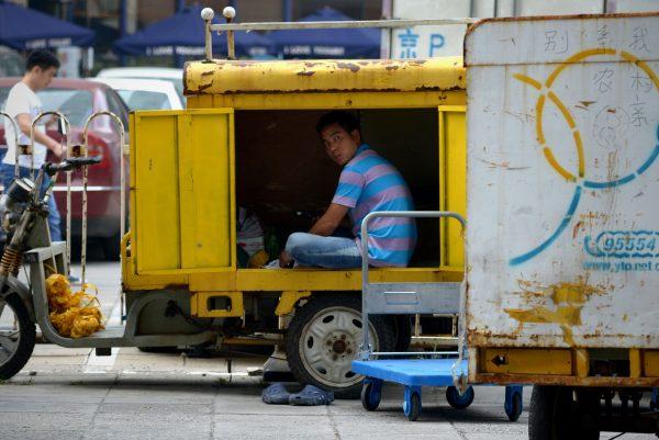 A delivery courier checks the packages inside his three-wheeled vehicle in Beijing on Aug. 18, 2014. (Wang Zhao/AFP/Getty Images)