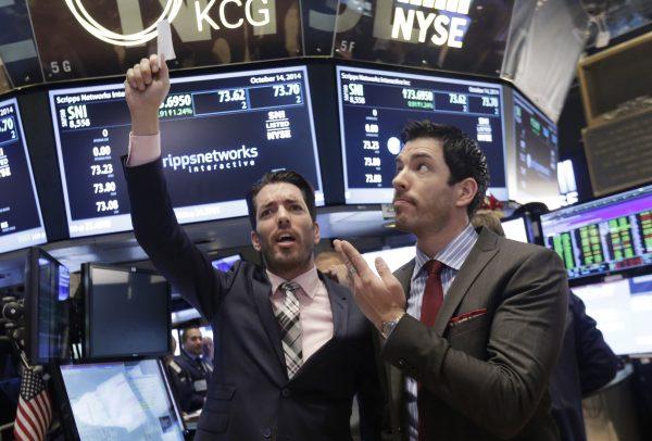 Jonathan Scott (L) and Drew Scott, of HGTV's "Property Brothers" cable television show, mimic traders as they visit the post that handles Scripps Networks Interactive, on the floor of the New York Stock Exchange, after ringing the opening bell, Tuesday, Oct. 14, 2014. (AP Photo/Richard Drew)