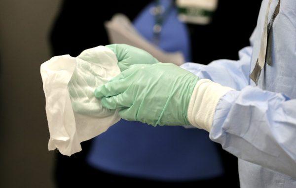 Registered nurse Keene Roadman, dressed in personal protective equipment, demonstrates bleach wiping the inner layer of gloves, after the outer gloves are removed during a training class at the Rush University Medical Center in Chicago on Oct. 16, 2014. (Charles Rex Arbogast/AP Photo)
